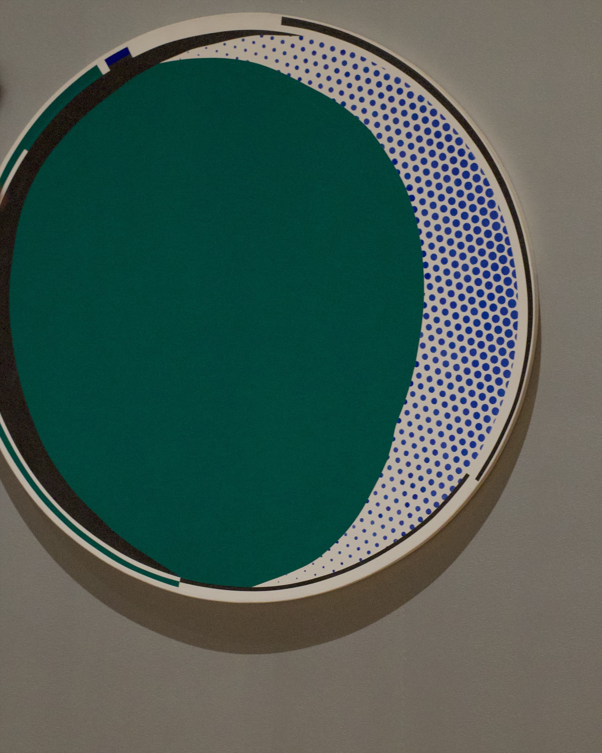 A round work on the wall that shows a mirror as a green field and dots