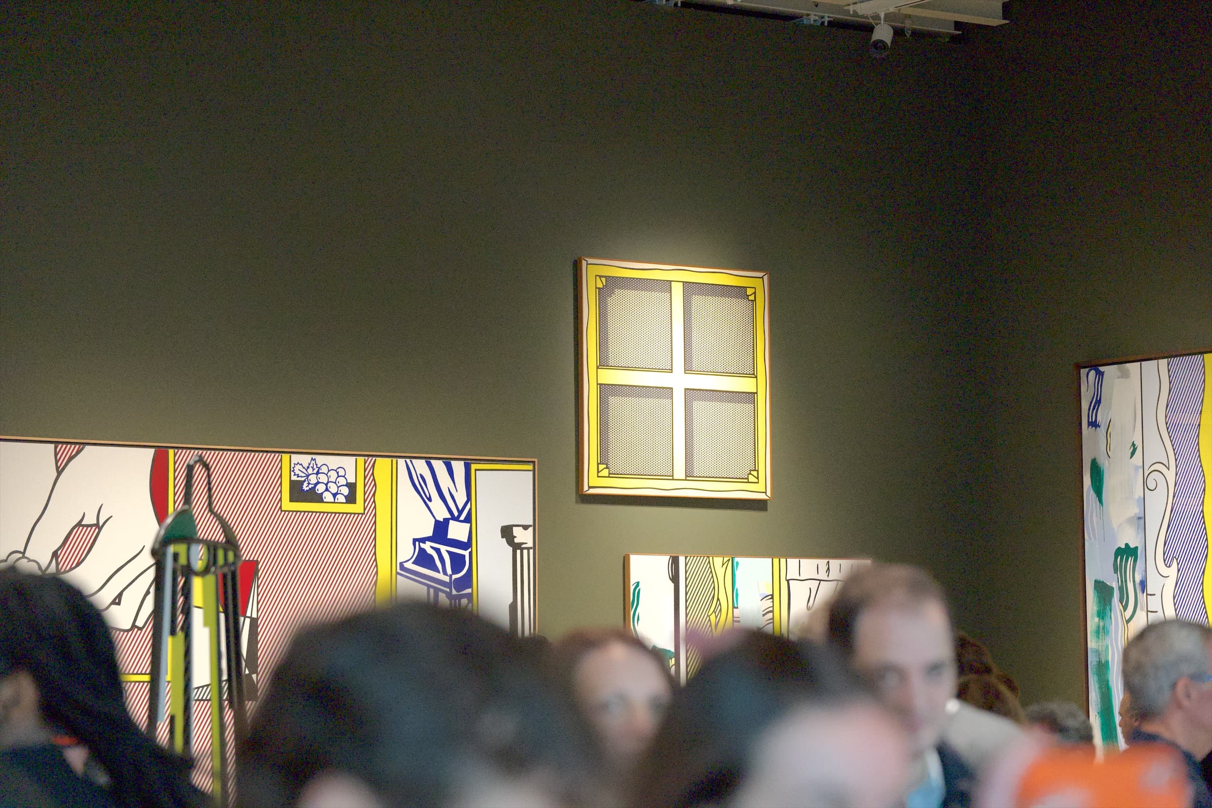 Visitors fill a gallery hung with a painting of a yellow window