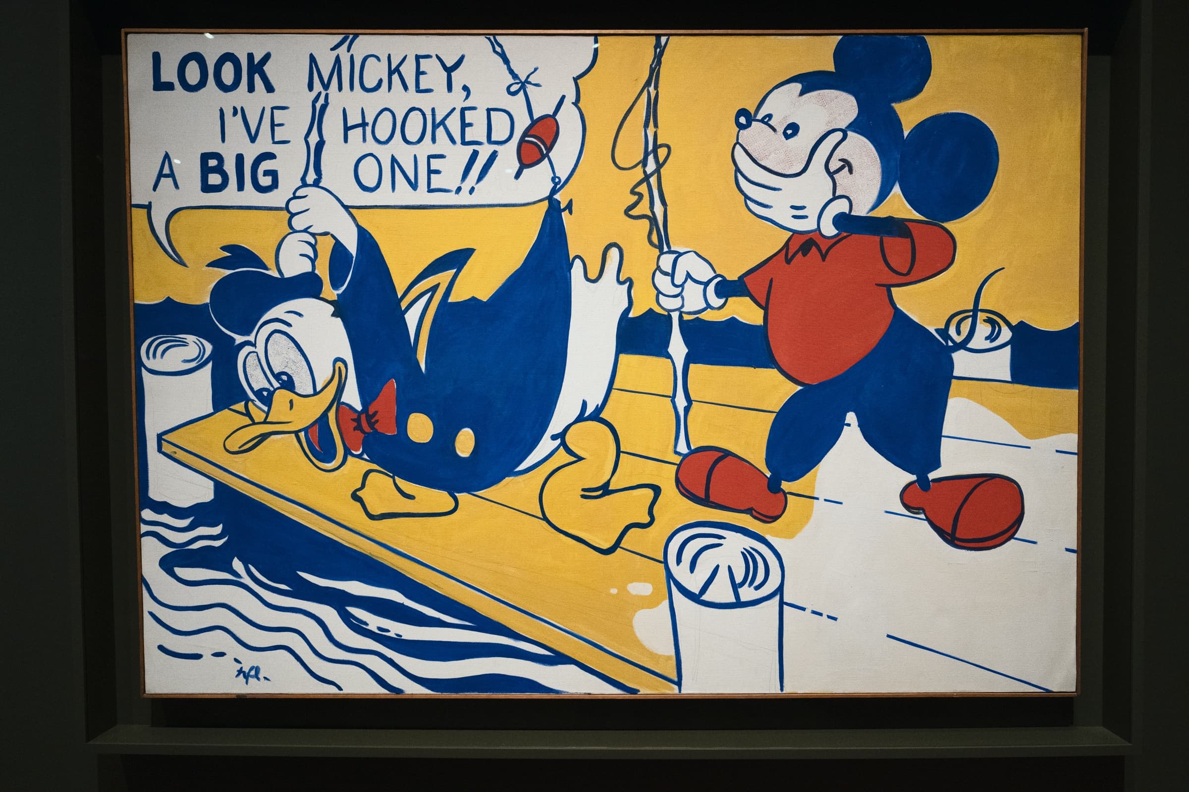 黄色い桟橋で釣り竿を引くドナルドと、口に手を当てて笑うミッキー。吹き出しに LOOK MICKEY, I'VE HOOKED A BIG ONE!!