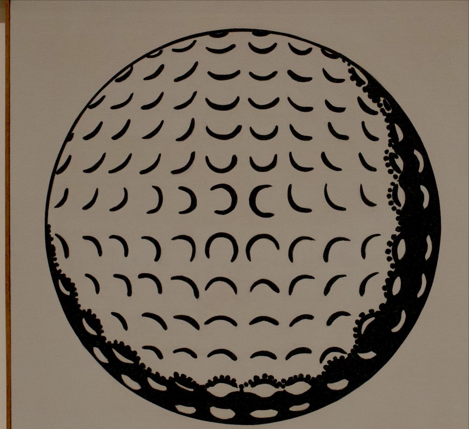 A golf ball whose dimples are drawn as crescents, in a white frame