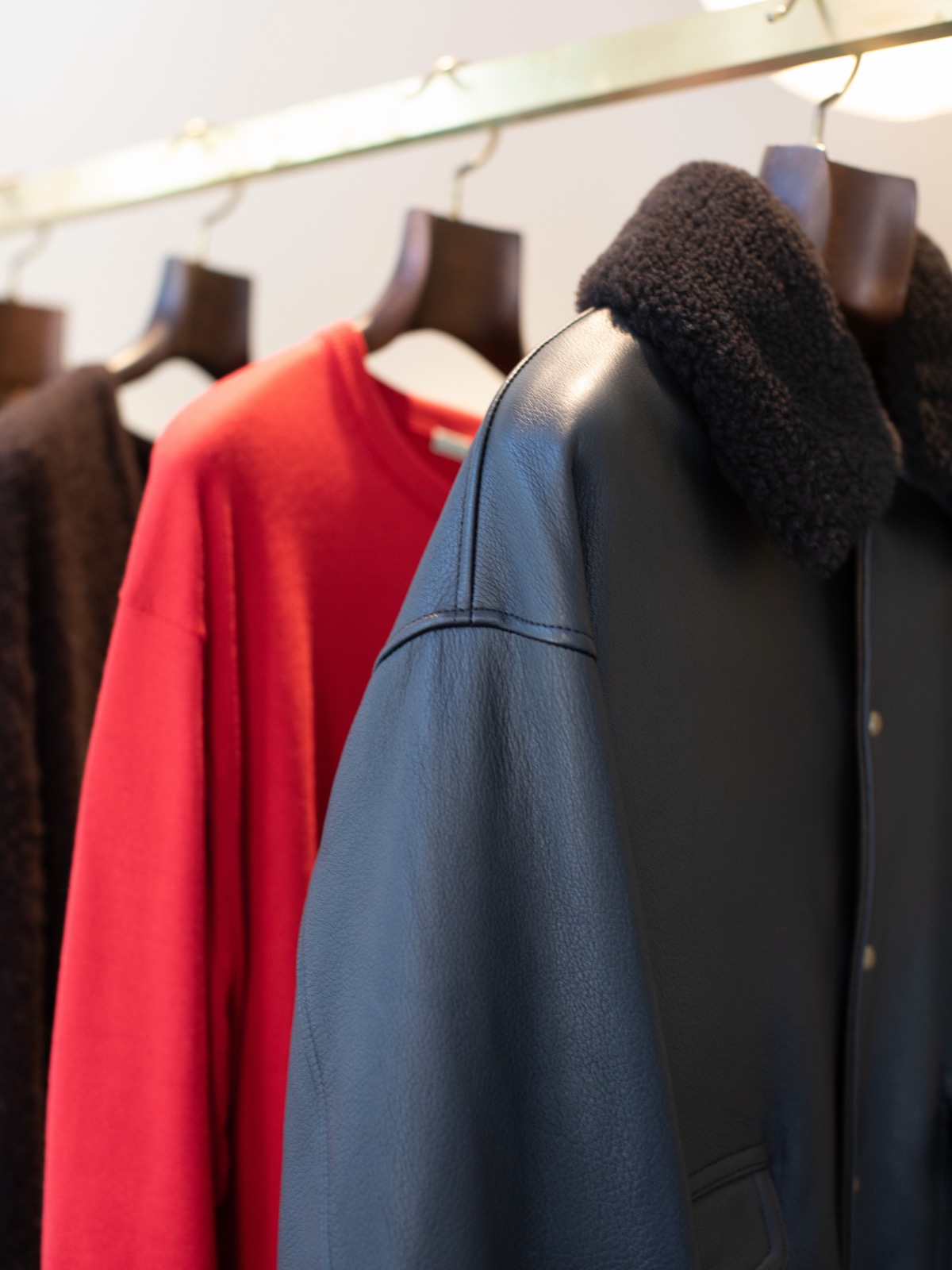 A red knit and a black leather jacket with a shearling collar