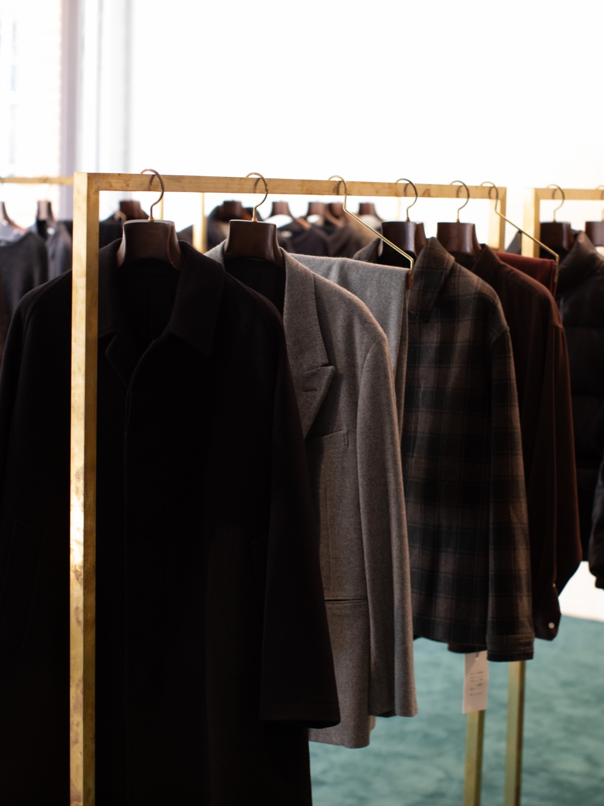 Coats and checked jackets on a brass rail