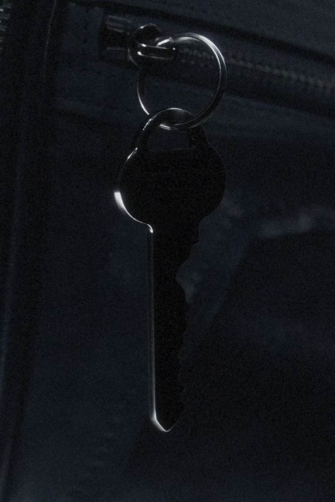 A key hanging from a zip on a black leather bag