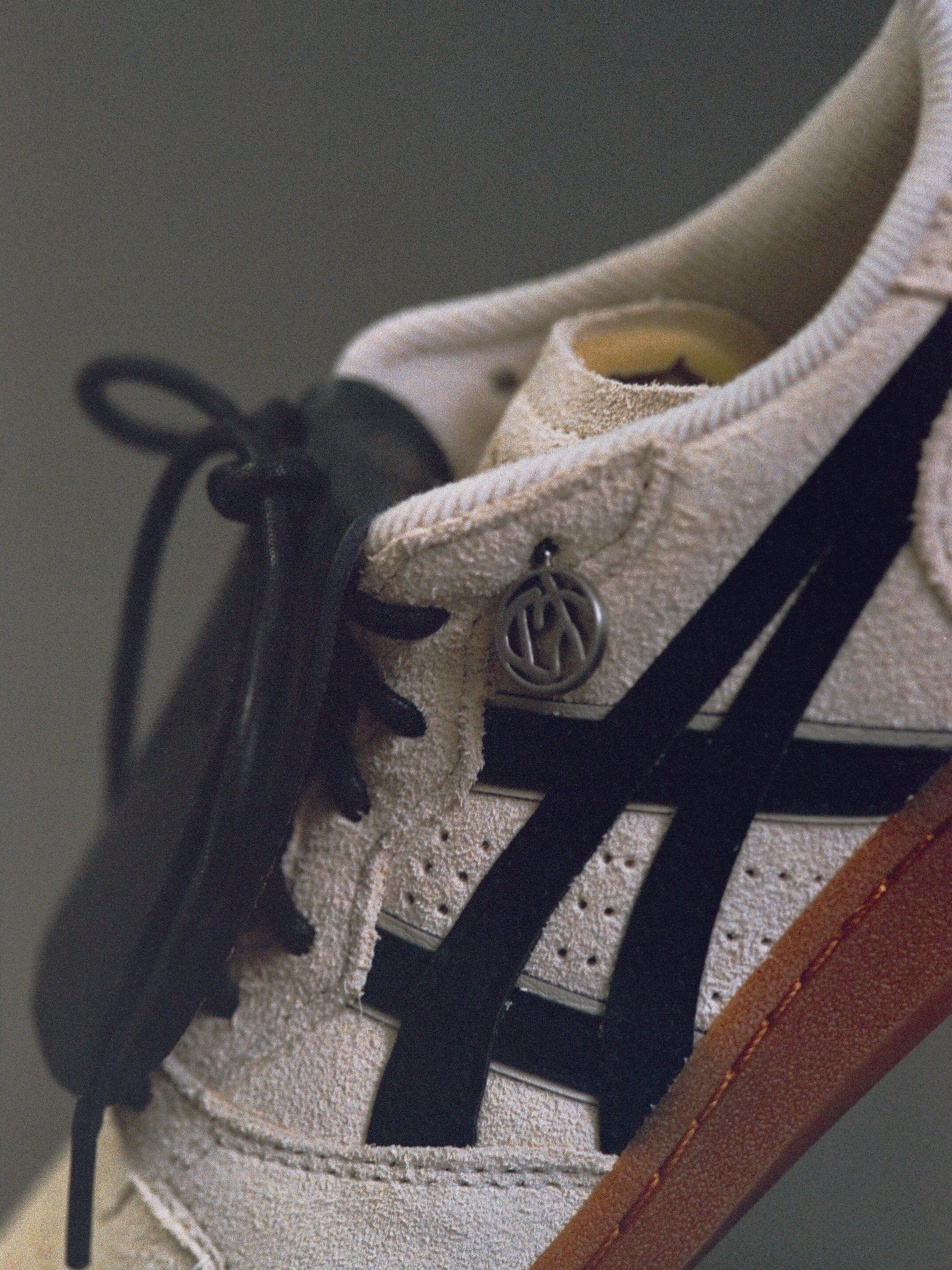 Side detail with black leather stripes and a round metal charm at the eyelet