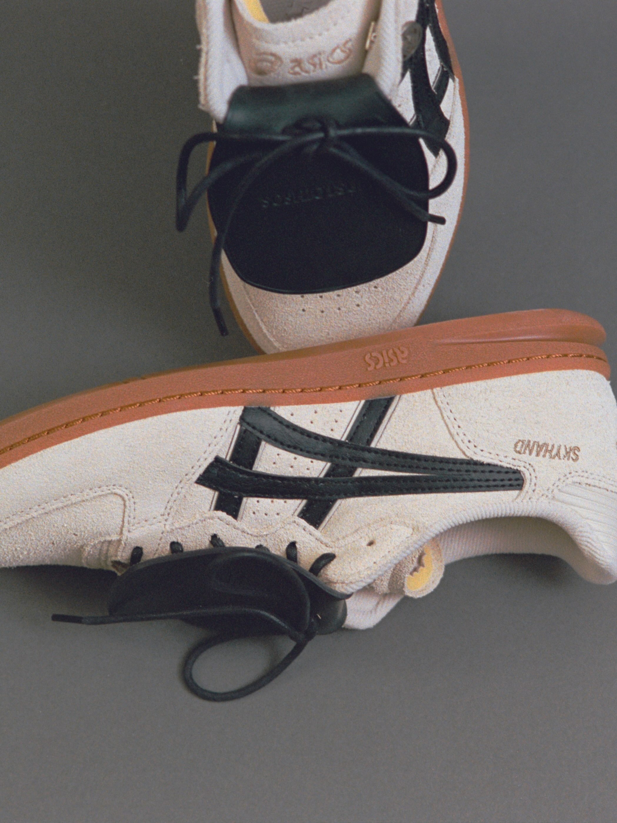 Side view of the sneaker showing black stripes and SKYHAND text on the gum-soled shoe