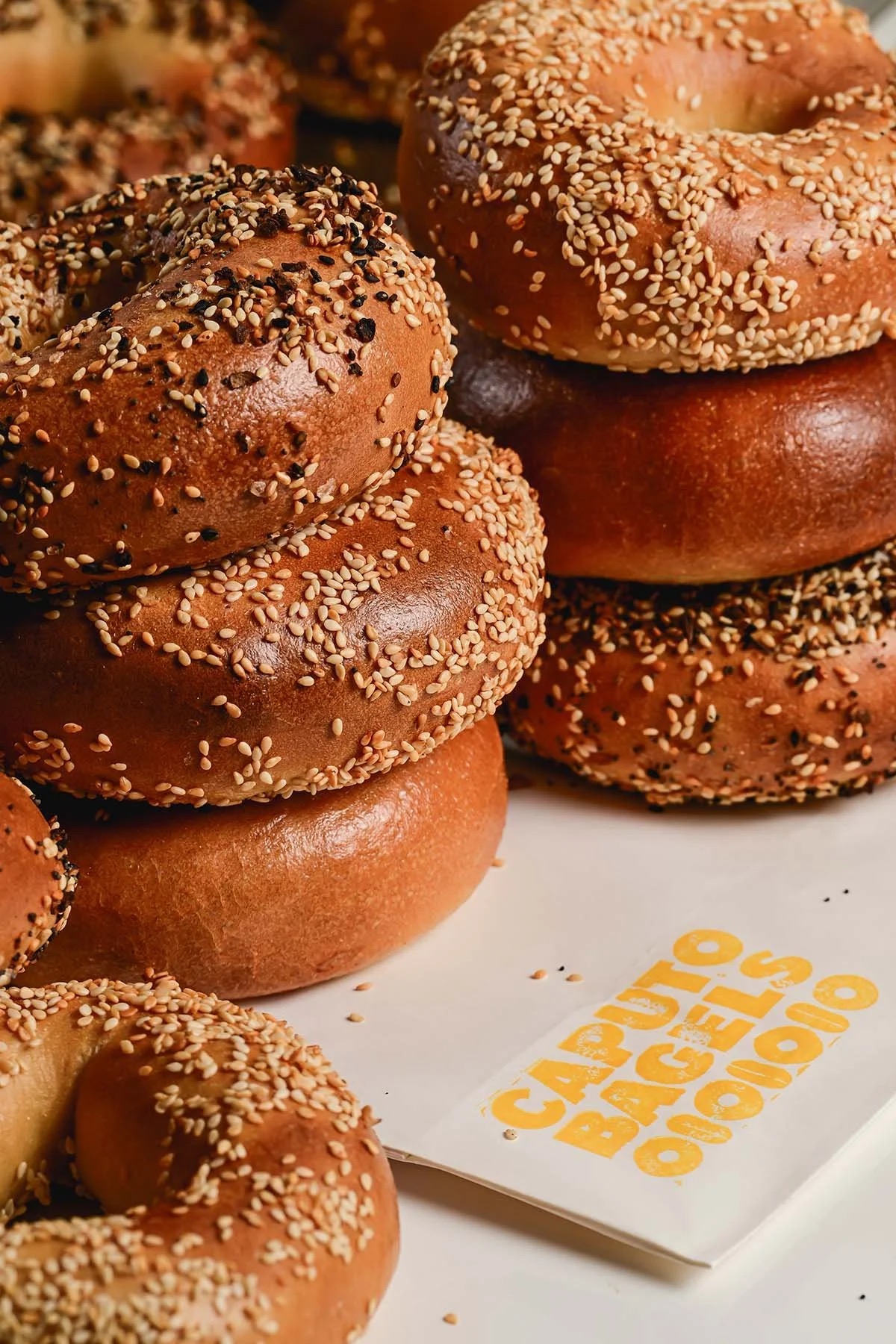 Hand-rolled sesame and plain sourdough bagels stacked at Caputo Bagels