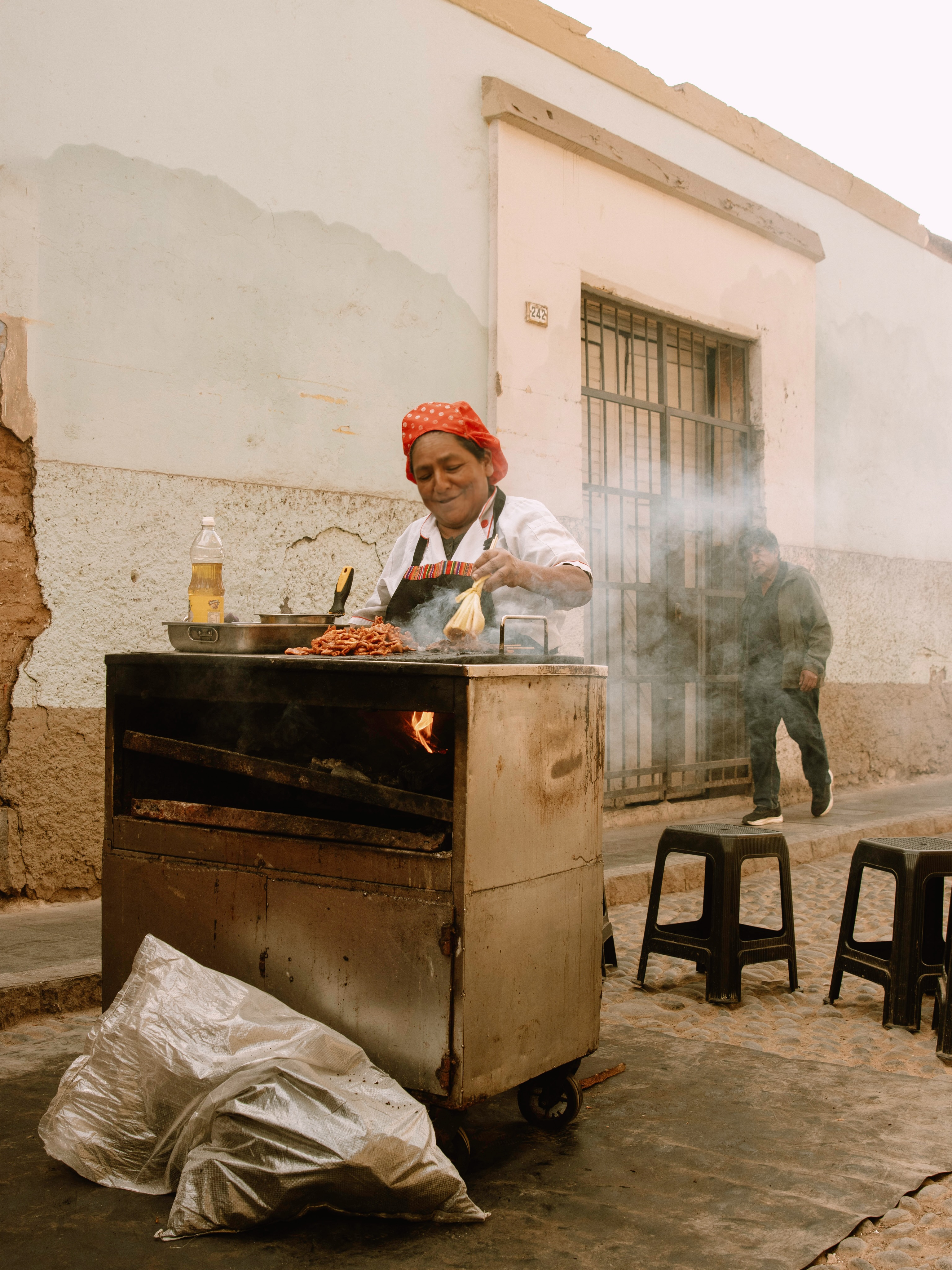 A street vendor grilling anticuchos over a charcoal cart in Peru