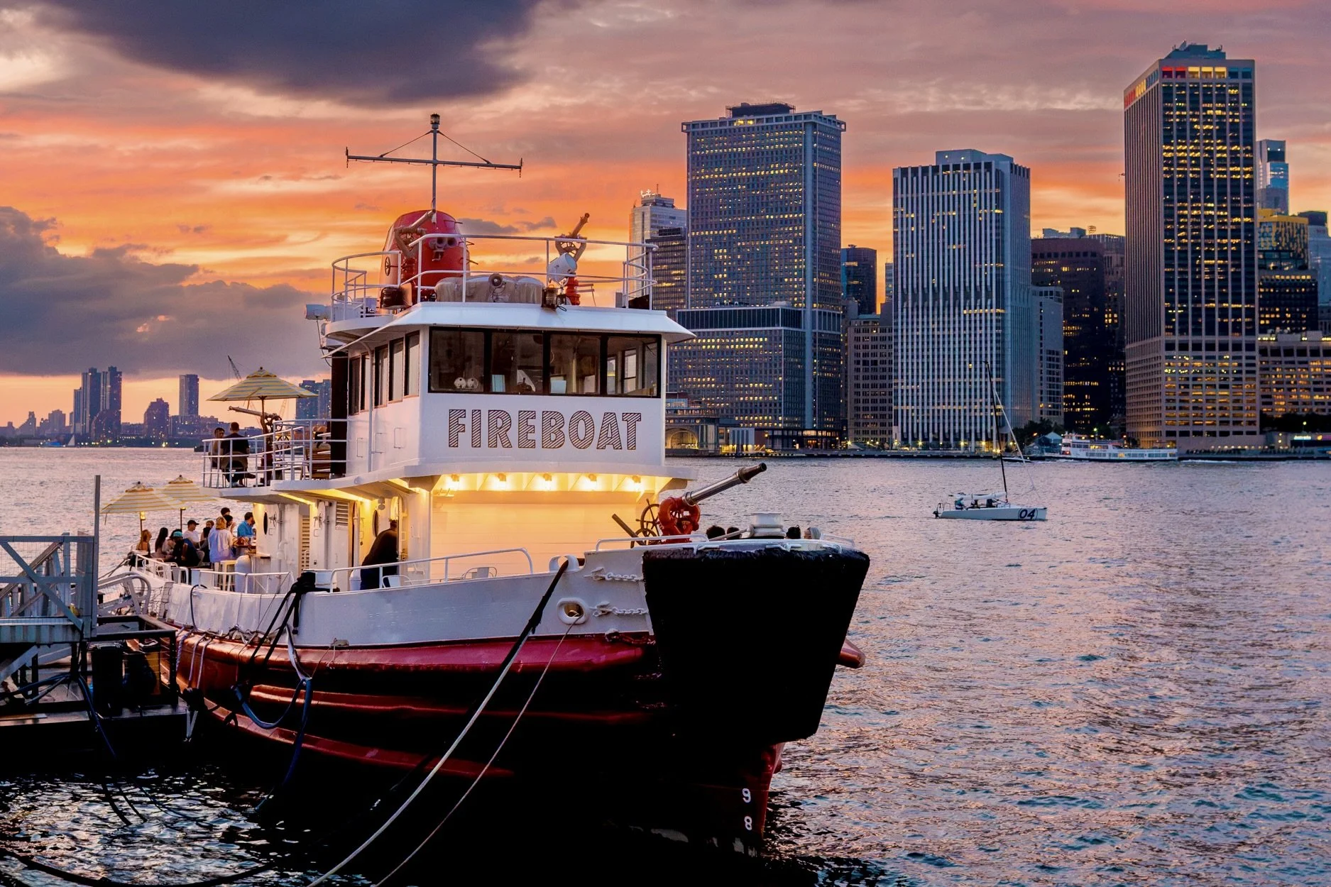 Fireboat docked at Pier 6 at sunset with the Lower Manhattan skyline behind