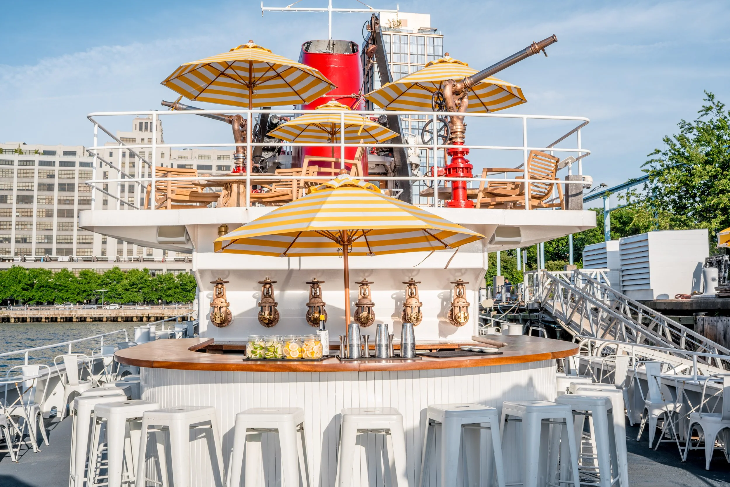 Fireboat's deck bar with brass fire-hose taps and striped umbrellas