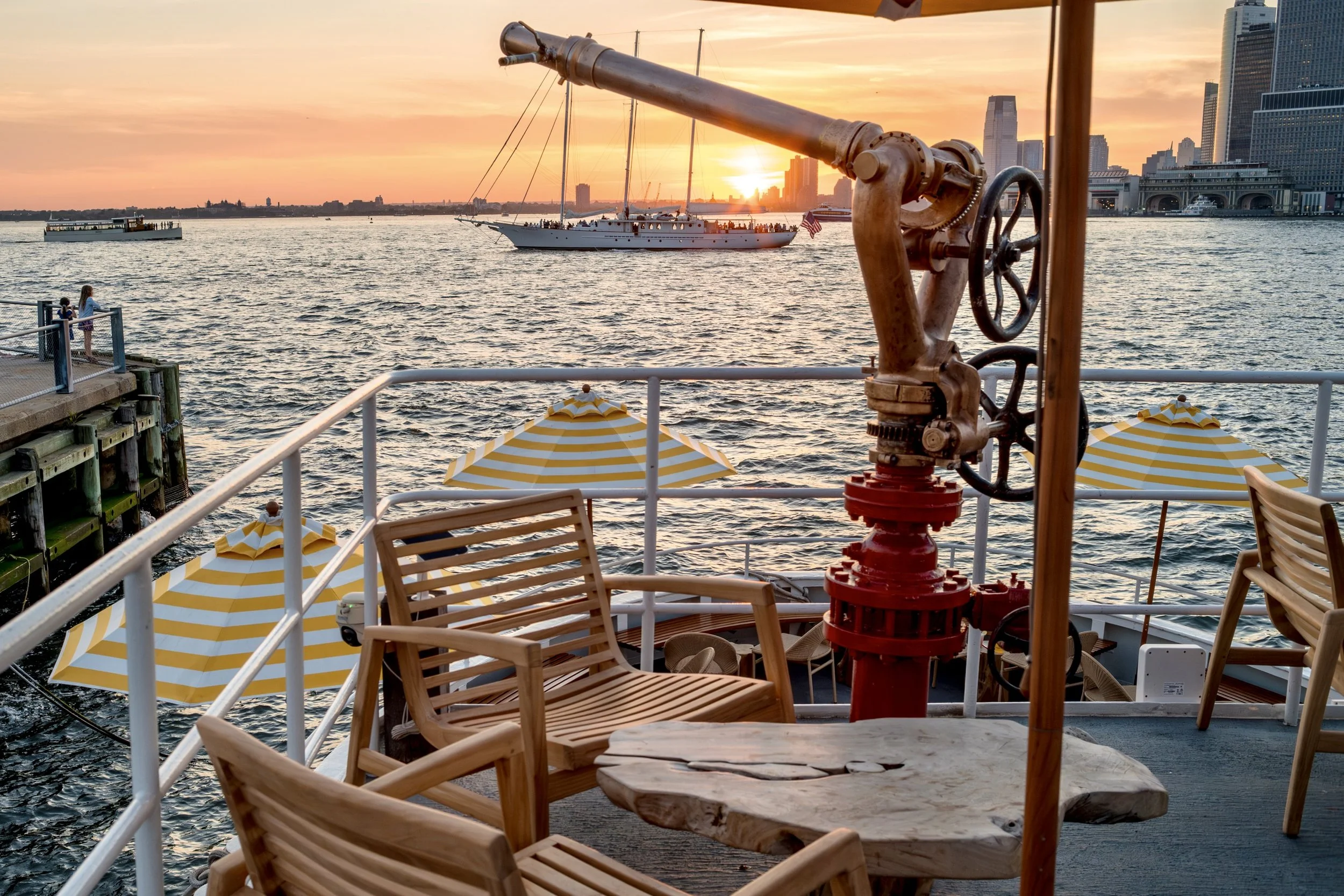 Brass fire monitor and teak seating on the upper deck at sunset
