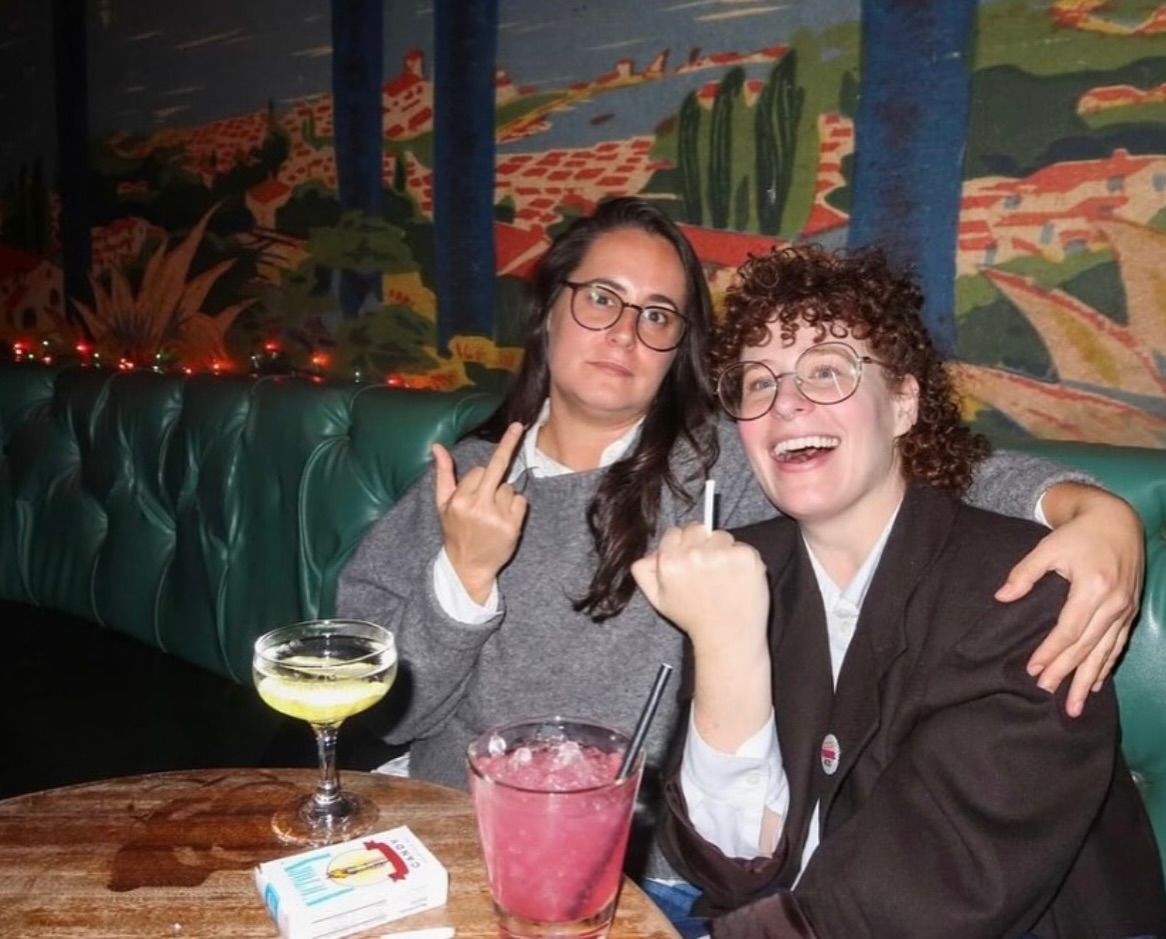 Two guests in a green booth with cocktails and a candy cigarette pack