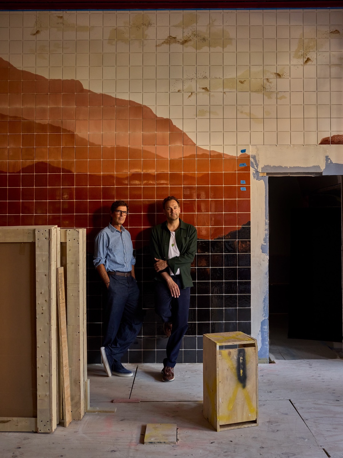 Two people standing in front of a tiled mountain mural inside HUMM