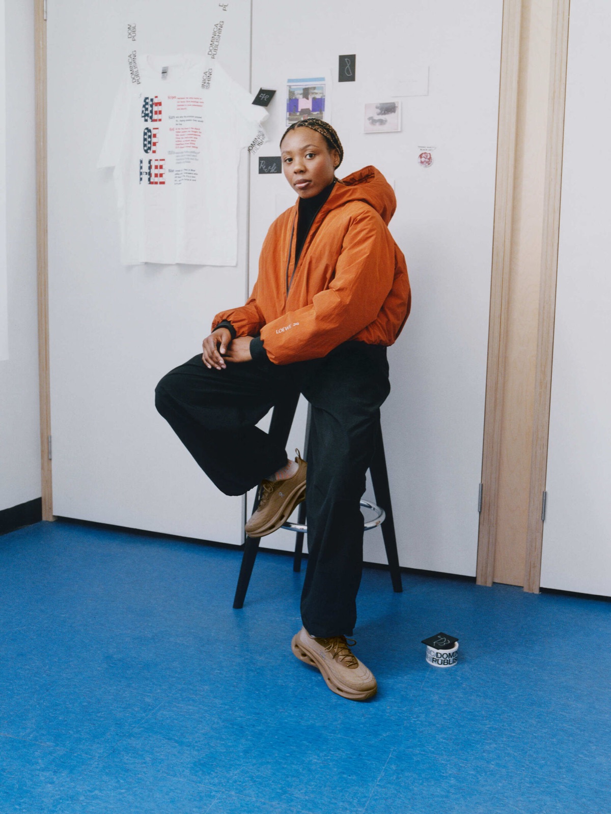 Artist in an orange LOEWE x On puffer jacket and hiking-inspired sneakers in a studio