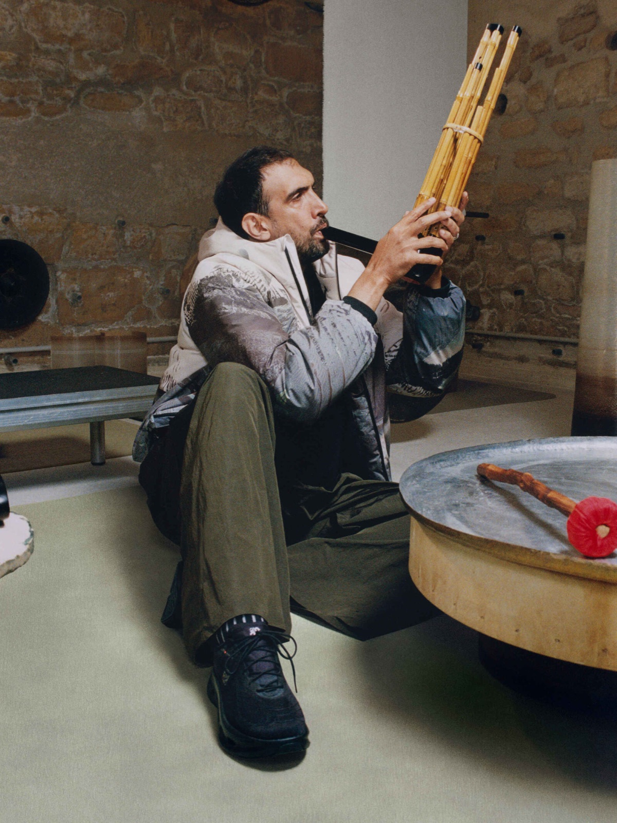 Artist playing an instrument in a LOEWE x On jacket in his studio