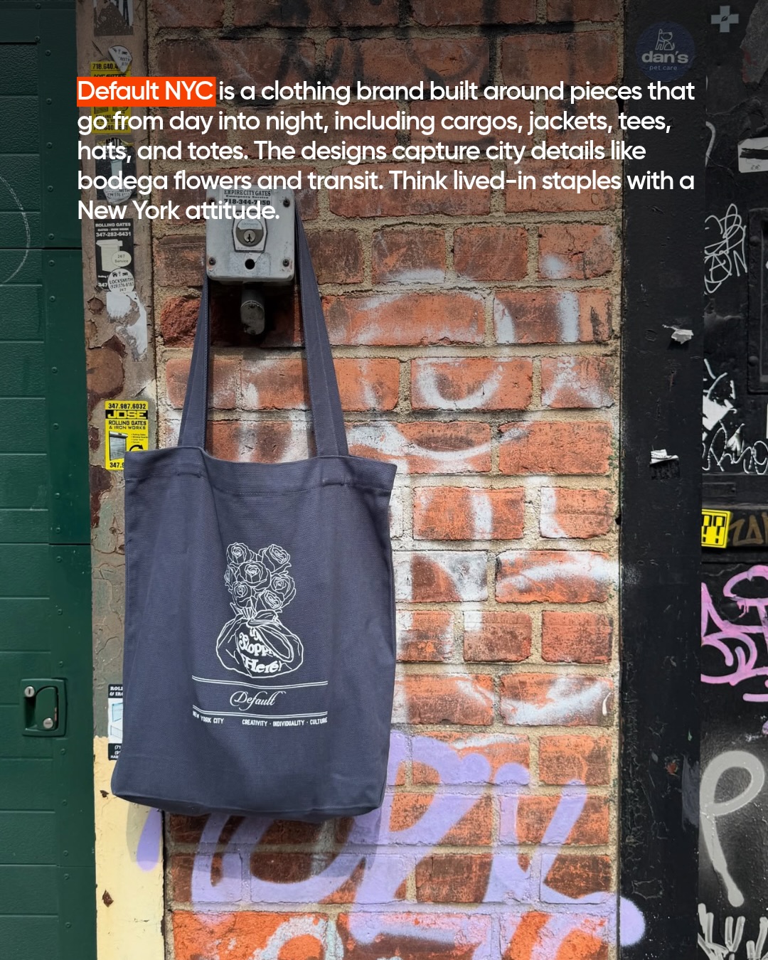 Default NYC navy tote bag with rose bouquet print hanging on a brick wall