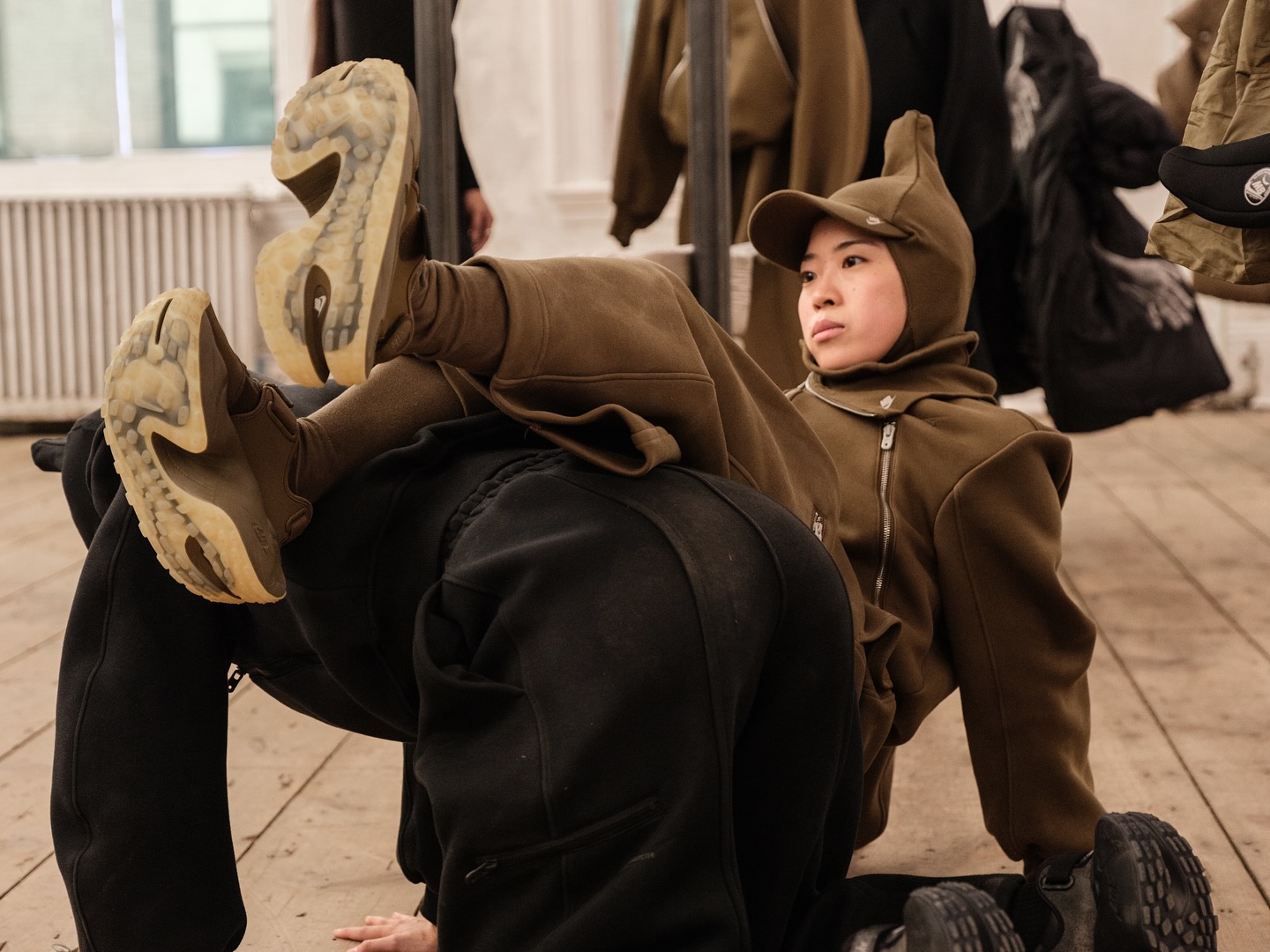 Dancers in olive tracksuits and brown sneakers with pale soles
