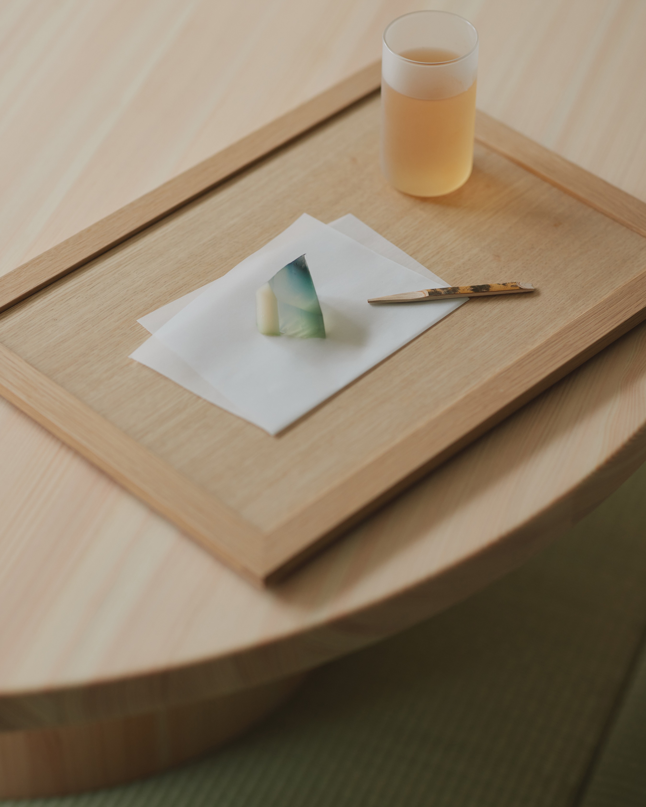 Wagashi sweet and a glass of tea on a wooden tray at Oyado MAS