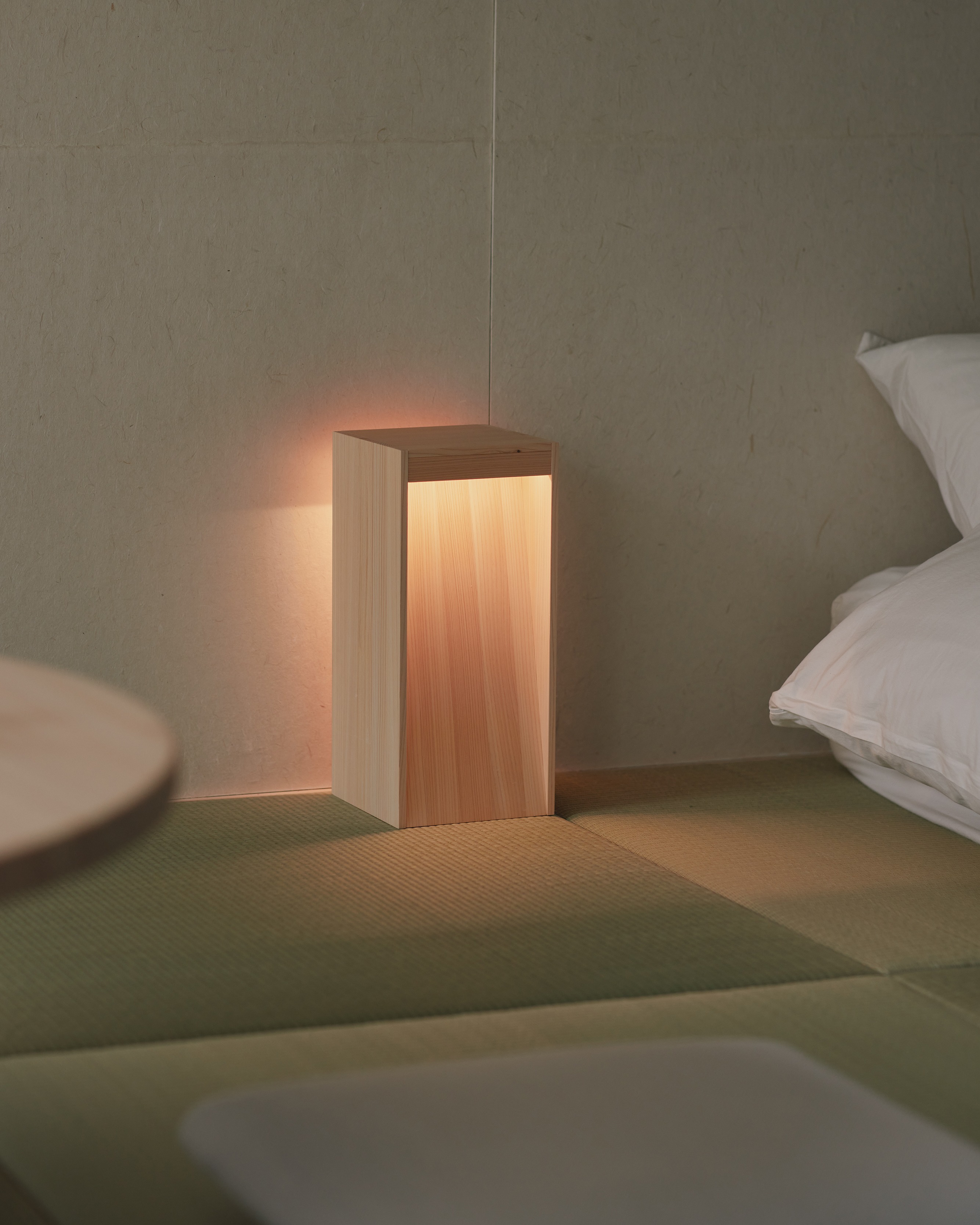 Cypress lamp glowing beside a tatami floor and bedding