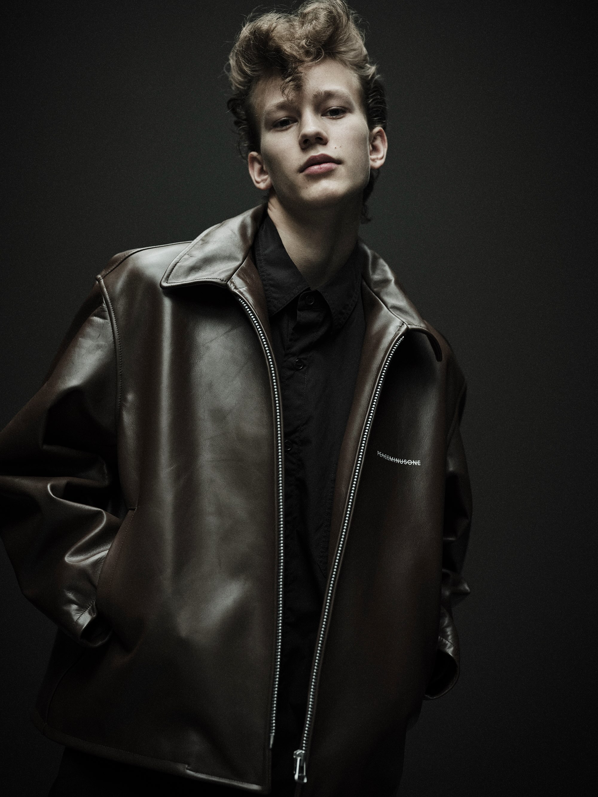 Front of the brown leather jacket with PEACEMINUSONE chest logo