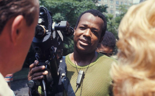Man operating a film camera outdoors in a still from the William Greaves series
