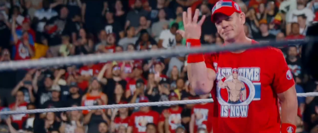 John Cena waving to the crowd in a red Last Time Is Now shirt during his 2025 farewell tour